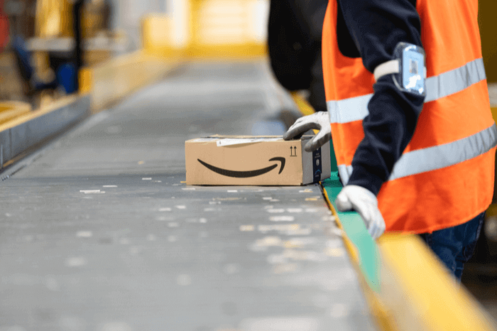 Amazon-Logistik-Mitarbeiter mit Paket an einem Fließband