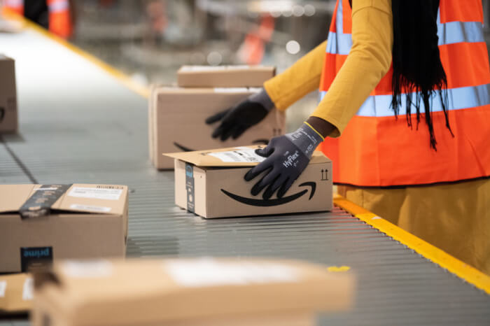 Amazon-Mitarbeiterin mit Paketen auf Förderband