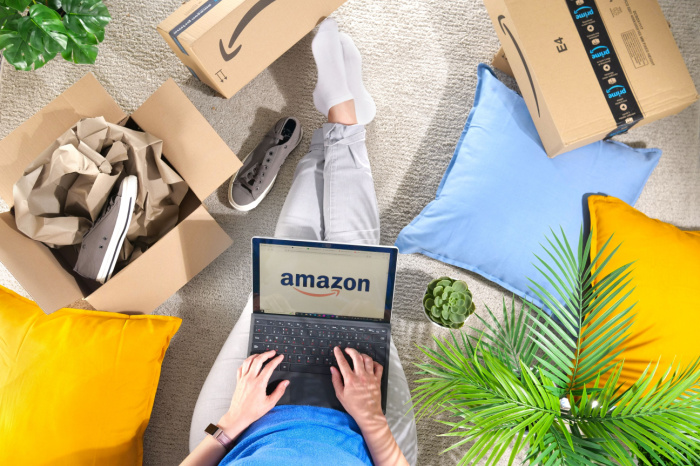 Stapel von Amazon Prime-Pakete, Frau mit Laptop