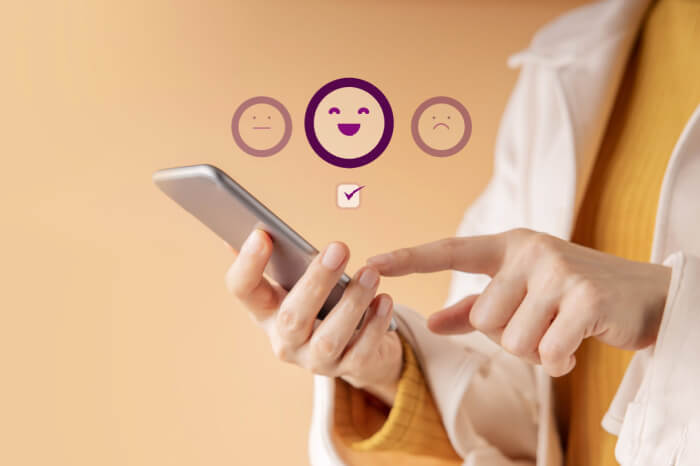 Person klickt symbolisch Emojis auf dem Smartphone an für Feedback