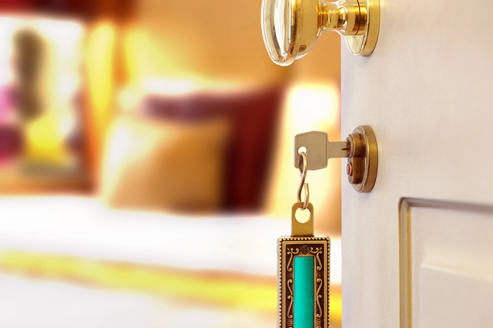 Halb geöffnete Hotelzimmertür mit golden verziertem Schüssel