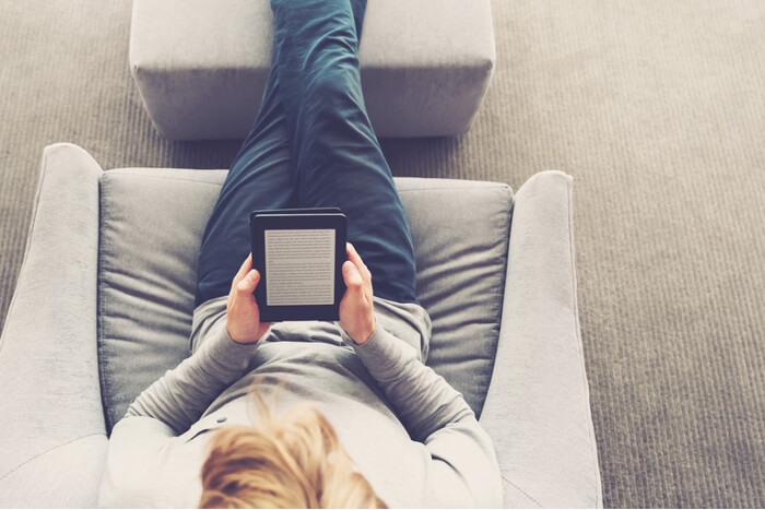 Frau auf Sofa mit einem E-Book-Reader in den Händen